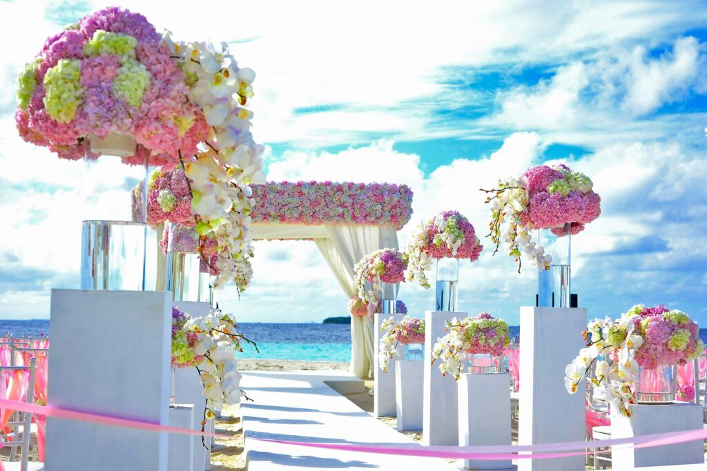Beautifully decorated beach wedding setup with vibrant flower arrangements by the sea.